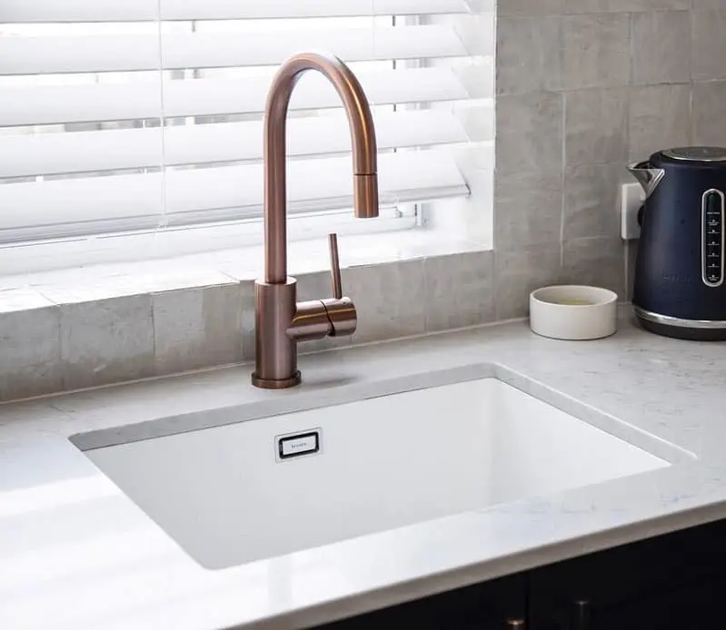 Flush white sink and brass tap detail in a completed Bondi apartment kitchen