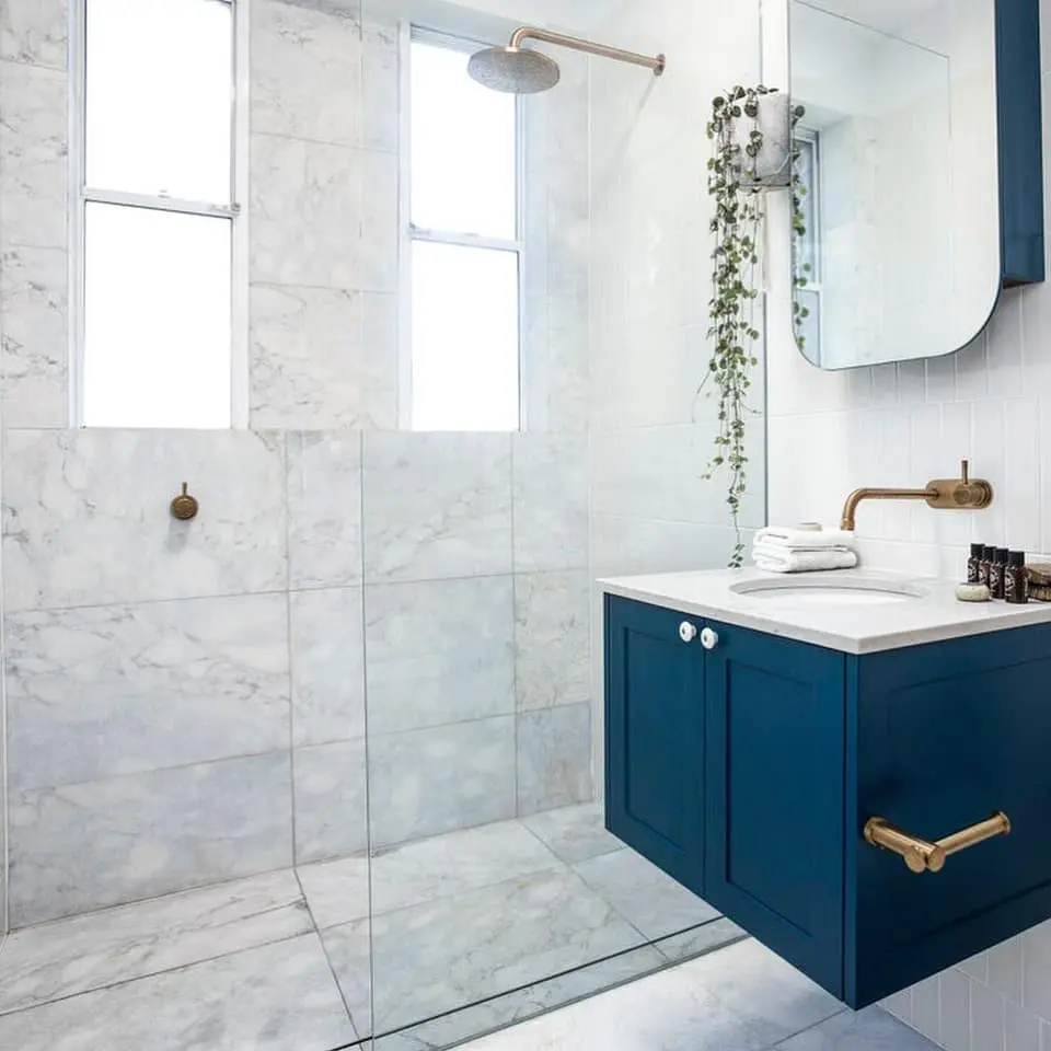 Blue vanity, timber door and glazed shower within a Bondi apartment bathroom
