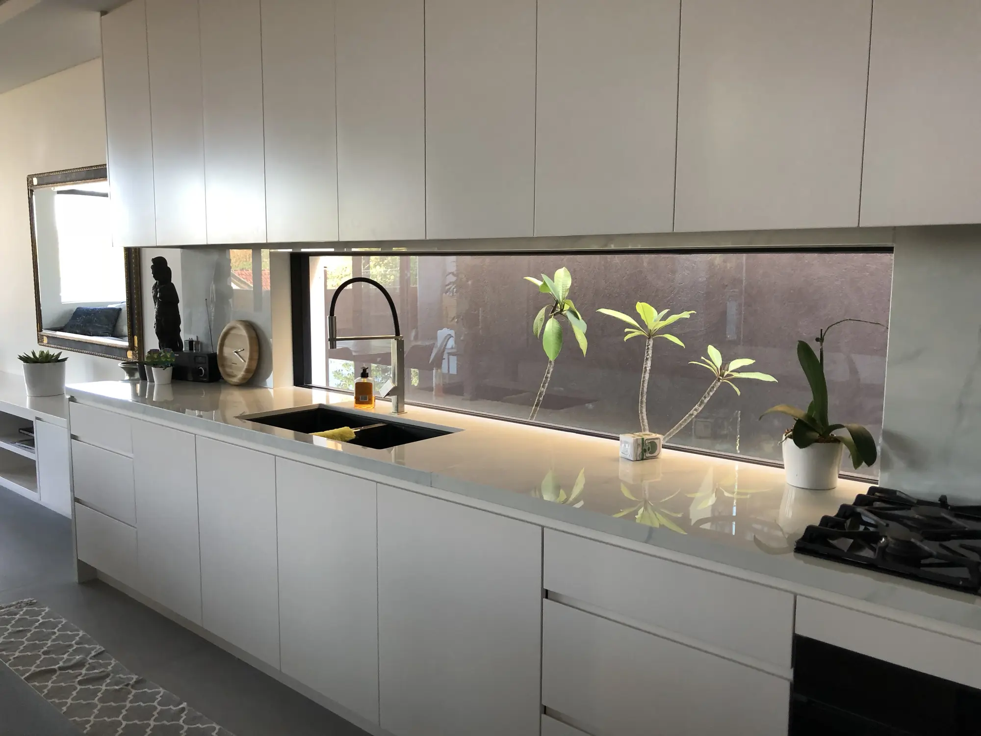 Handle-free kitchen cabinetry and stone splashback at a Kensington residence